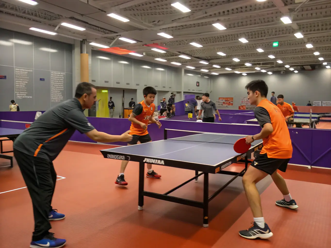 A vibrant photograph capturing a community table tennis training session in progress, showcasing participants of various ages and skill levels actively engaged in a friendly match, with coaches providing guidance in the background.